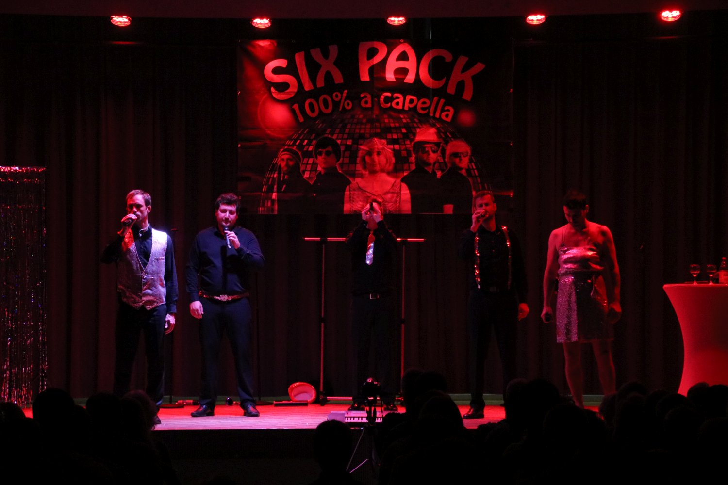 sixpack acapella in rotem Bühnenlicht vor dem Six-Pack-Banner